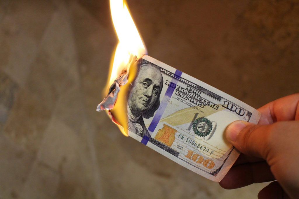 Hand hält brennenden 100 US-Dollar Schein